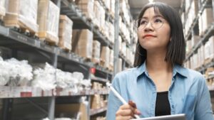 a woman working in procurement walks through a warehouse
